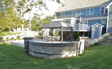 Blue colonial home with stone gazebo patio and stone wall