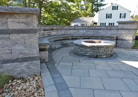 Stone and paver fire pit seating wall in a backyard
