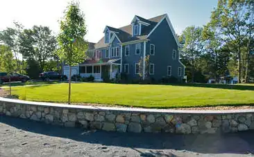 Home with a fieldstone wall bordering a manicured lawn