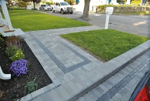 Paver walkway with bordered edging along a front lawn