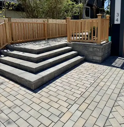 Wide paver steps to a deck with wooden railing
