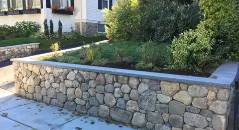Fieldstone retaining wall above a paver walkway