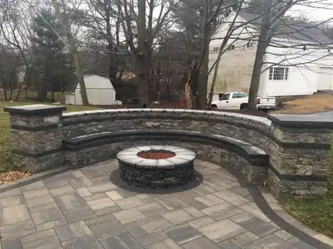 Stacked stone fire pit with curved seating wall