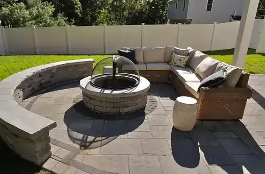A stone fire pit patio with built-in curved seating wall